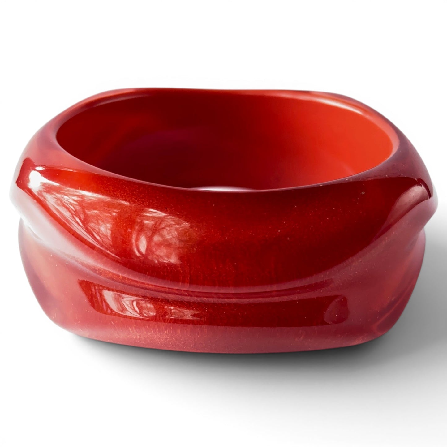 Cherry red Bakelite bangle showing circular inner bore with orange-red interior and smooth unfinished surface, top-down angle
