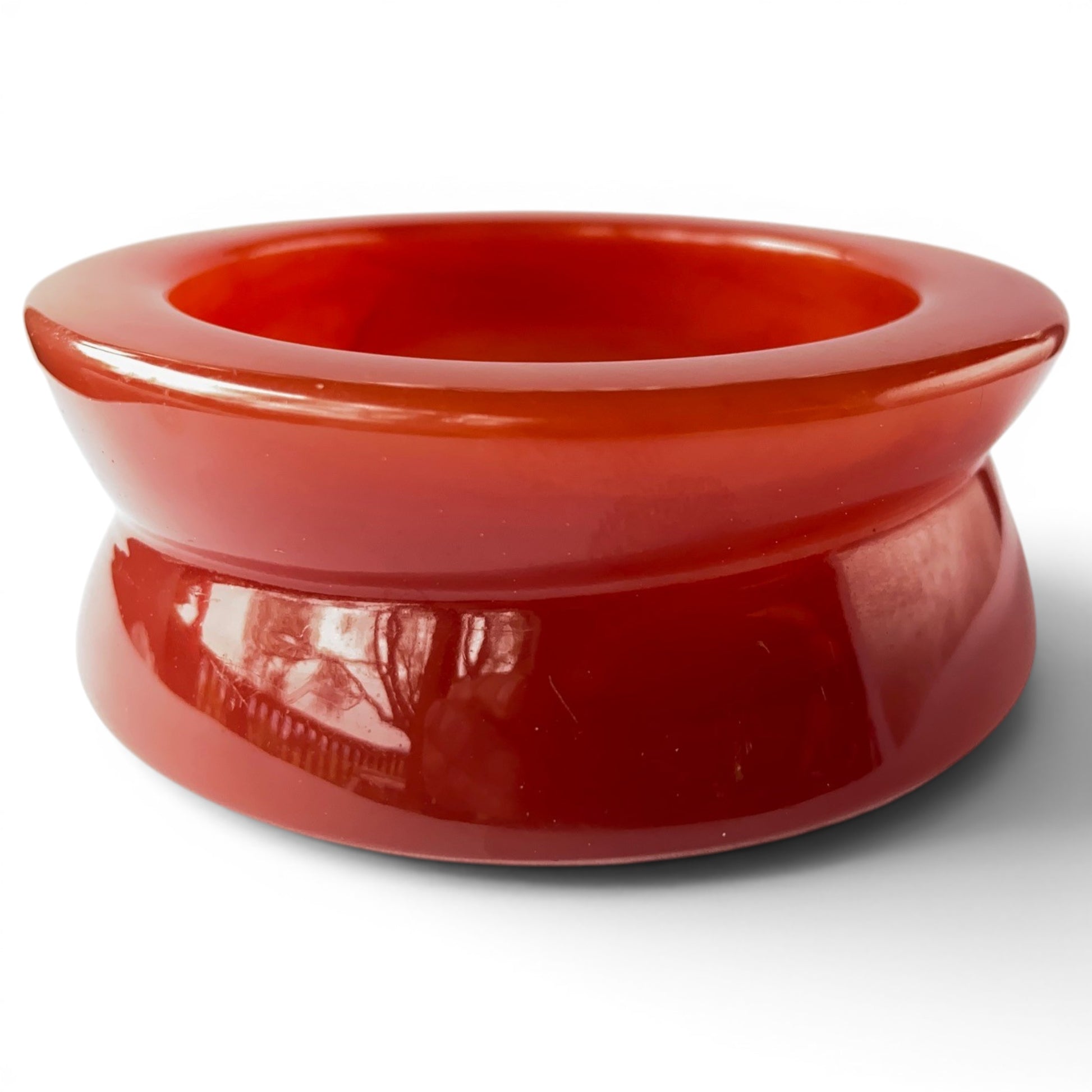 Wide chunky red-orange Lucite bangle with spool profile and high-gloss finish, gold MONET tag on inner rim