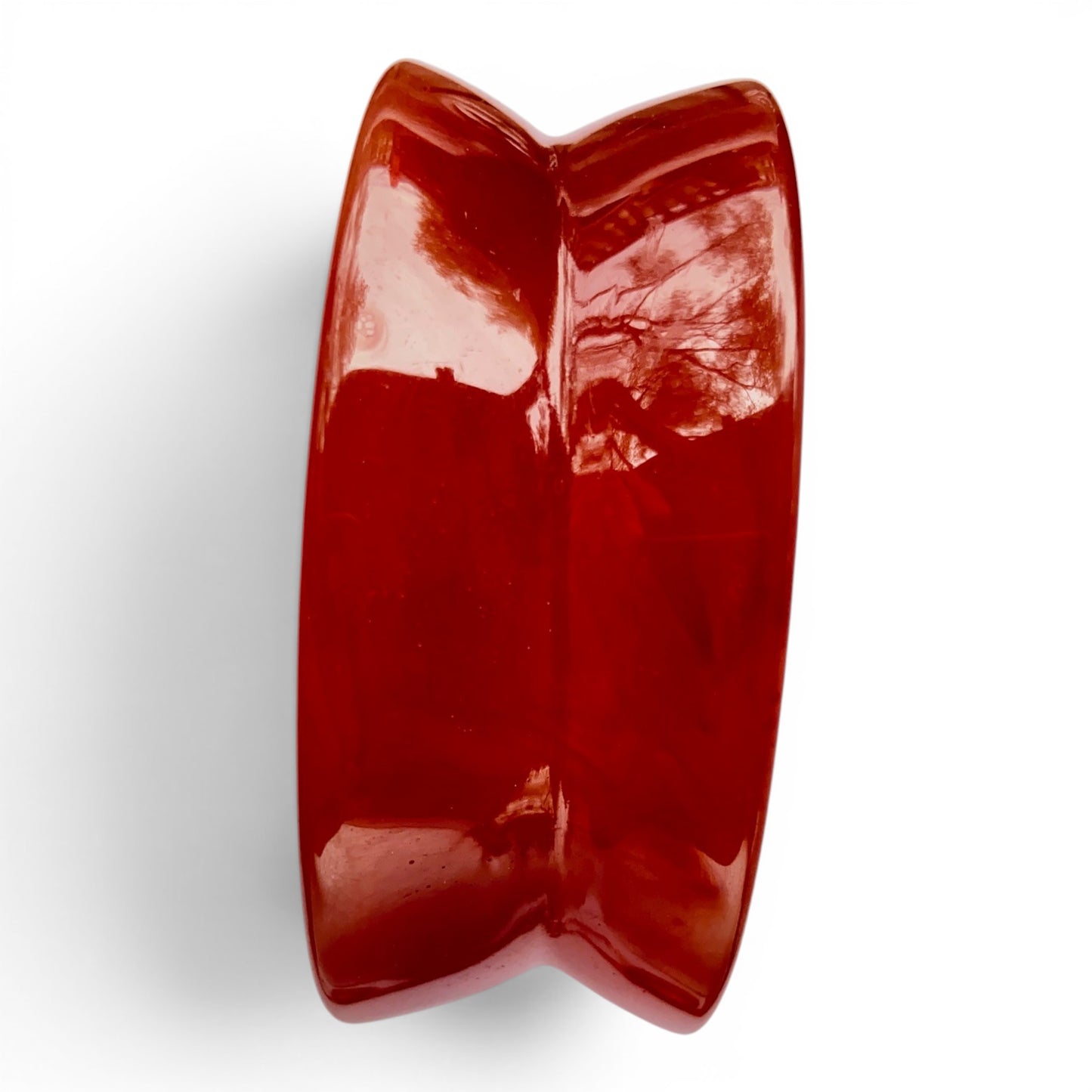 Close-up of gold-tone copyright MONET metal tag affixed to interior rim of deep red Lucite bangle