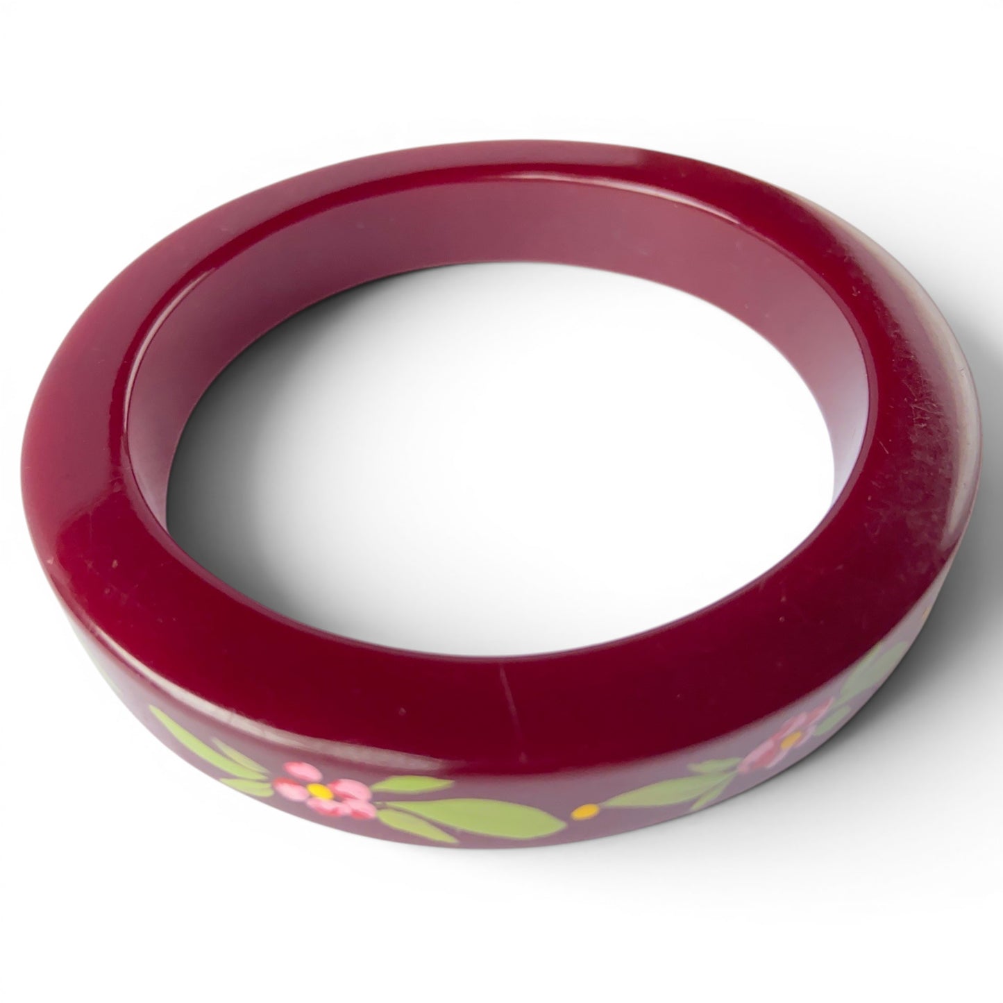 Side-angle view of burgundy lacquered bangle showing slightly squared cross-section profile and glossy painted surface