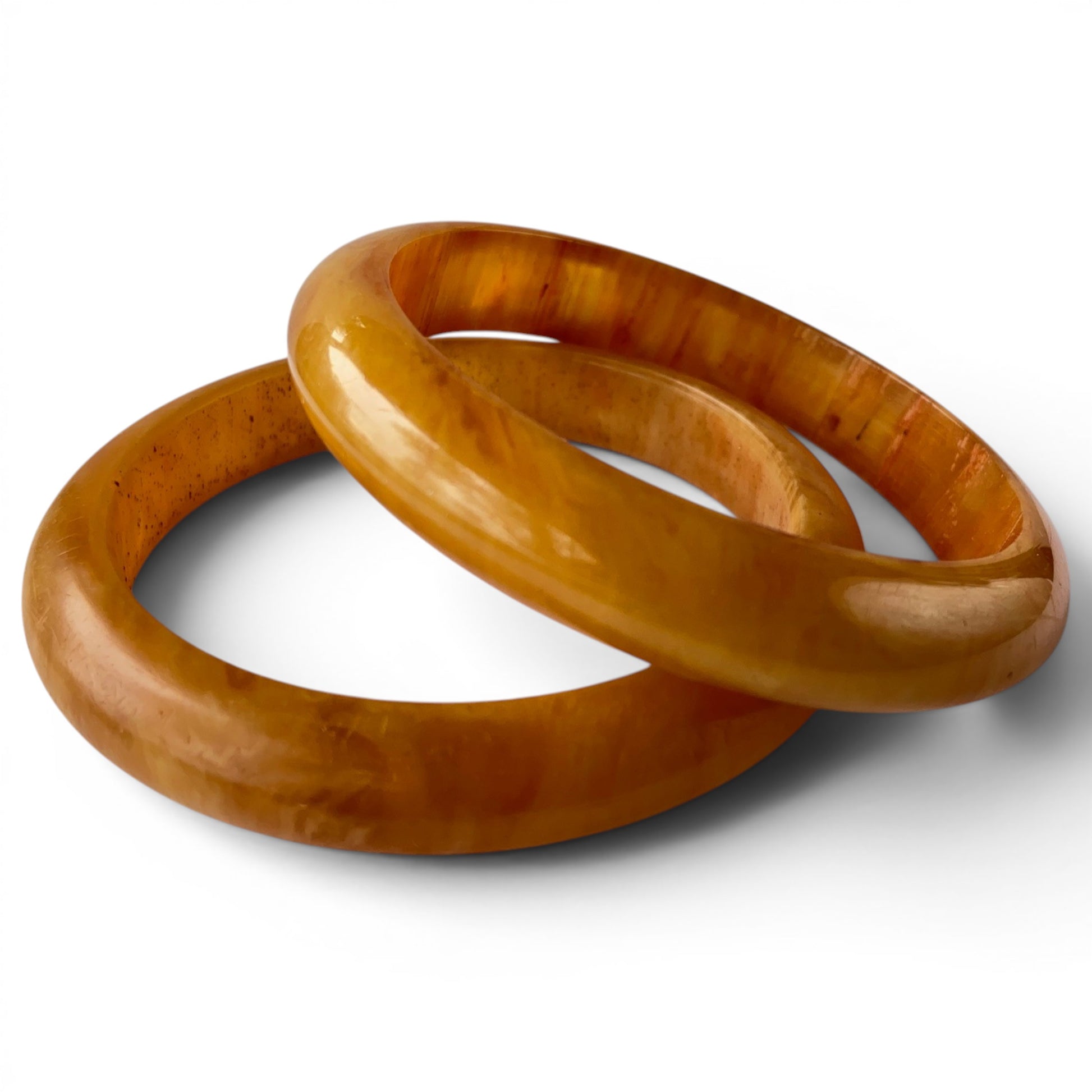 Pair of wide carved Bakelite bangles with amber and reddish-brown marbled swirling pattern, high-gloss polished surface