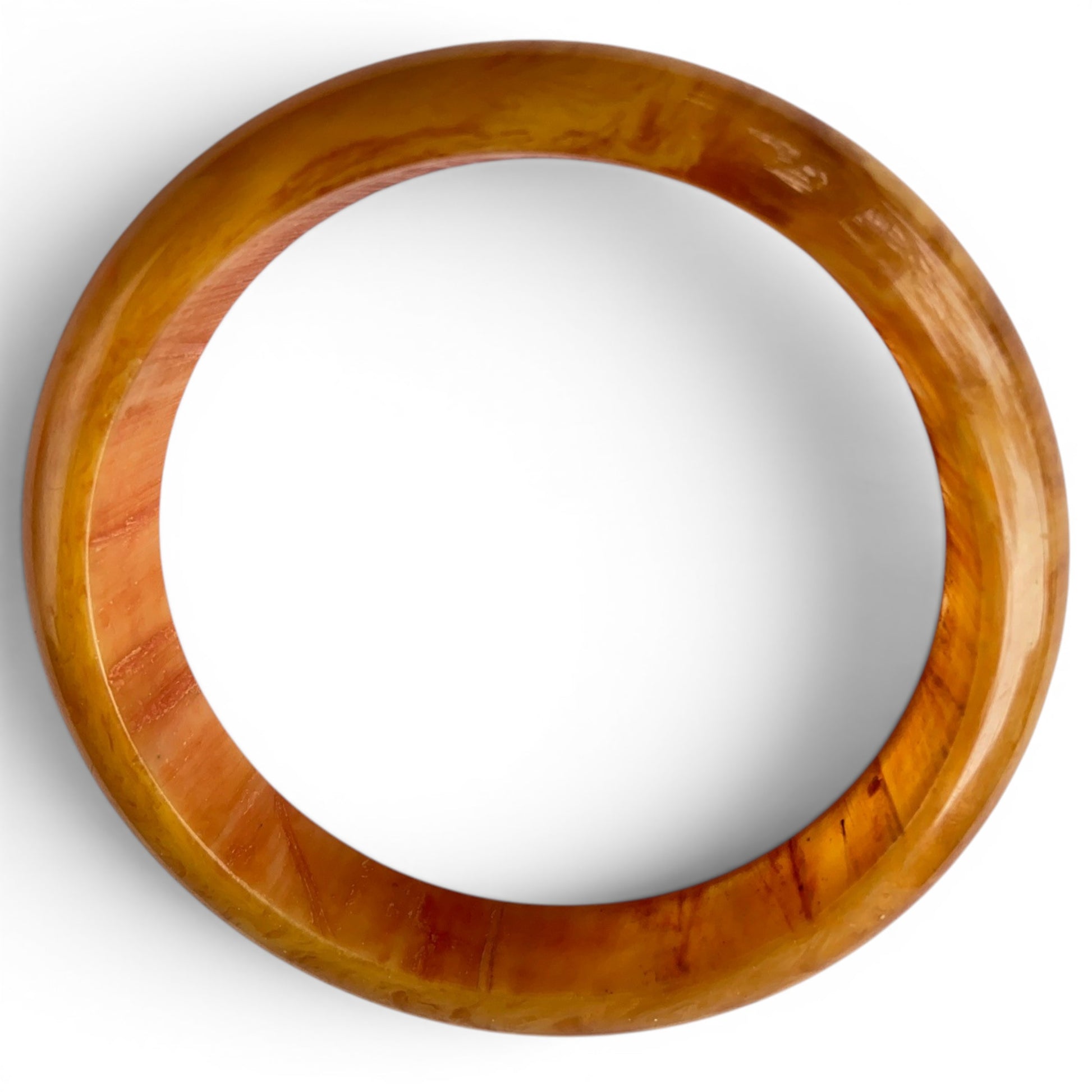 Close-up of Bakelite bangle surface showing natural mottling, amber-to-orange coloration, and largely intact high-shine po...