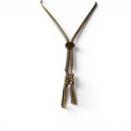 Gold-tone lariat necklace with wide foxtail chain, oval amber stone slider, and four tassel drops, displayed on a bust form