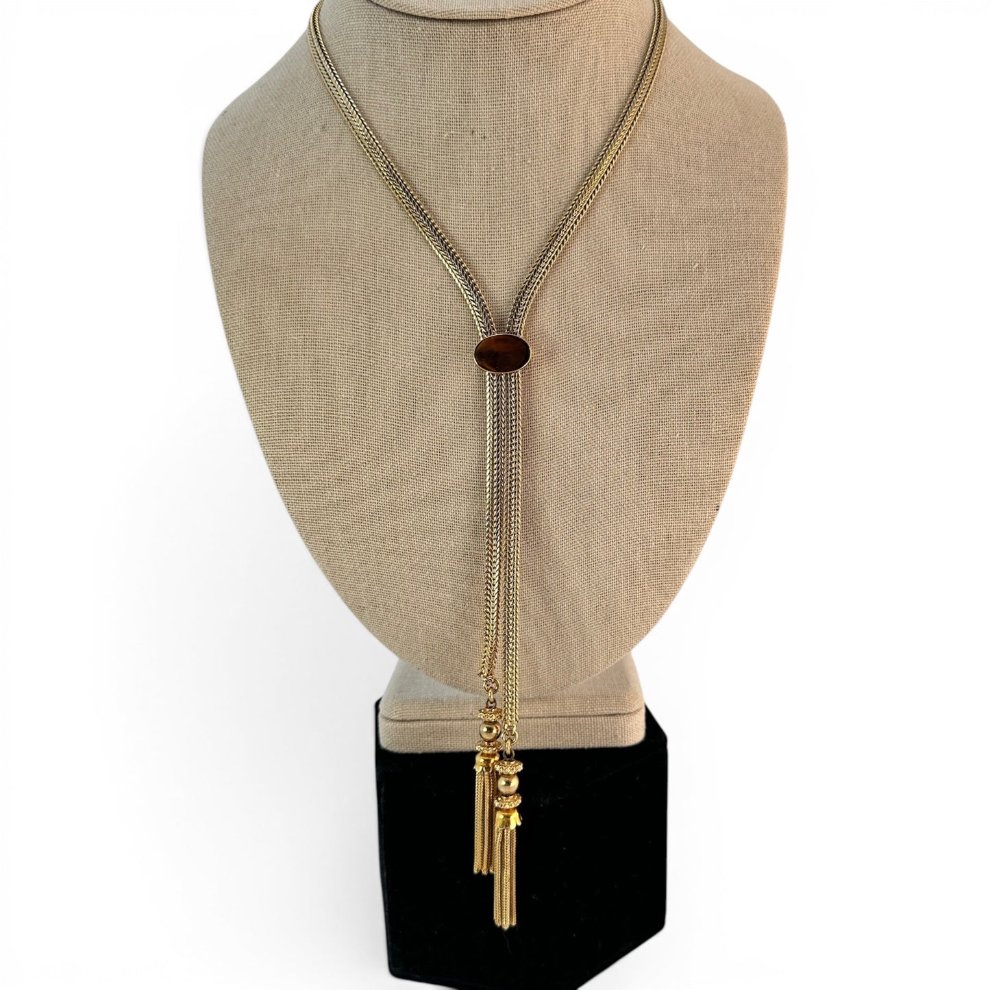 Detail of tassel pendant showing stacked rondelle spacers, polished gold ball bead, and fine chain fringe drops