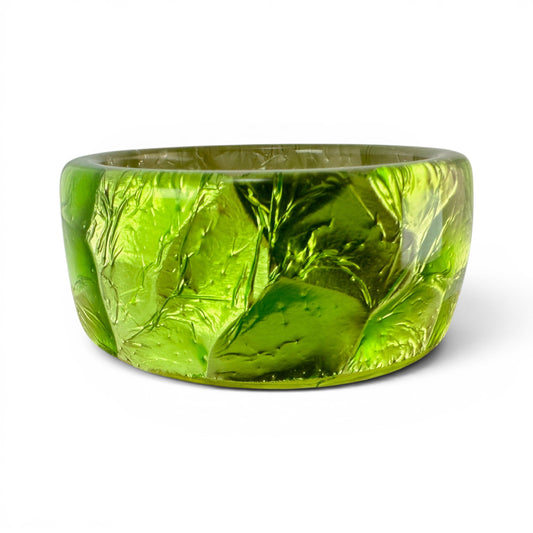 Clear Lucite bangle bracelet encasing chartreuse crinkled foil, irregular geometric textured outer surface, side profile view