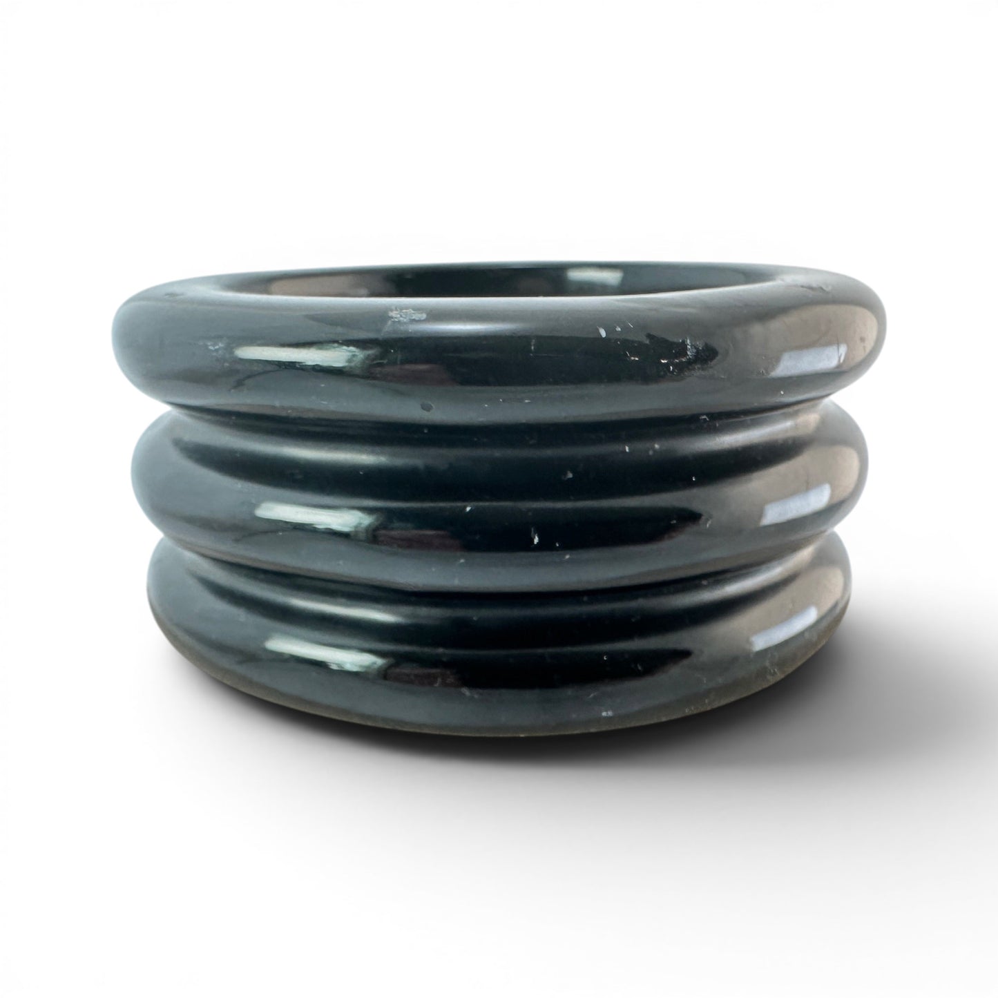 Close view of triple concentric raised ridges on black Bakelite bangle showing dark green-gray undertones in surface color...