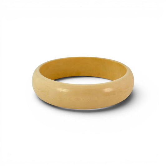 Close-up of rounded dome exterior of golden-yellow Bakelite bangle showing subtle surface grain and warm color variation