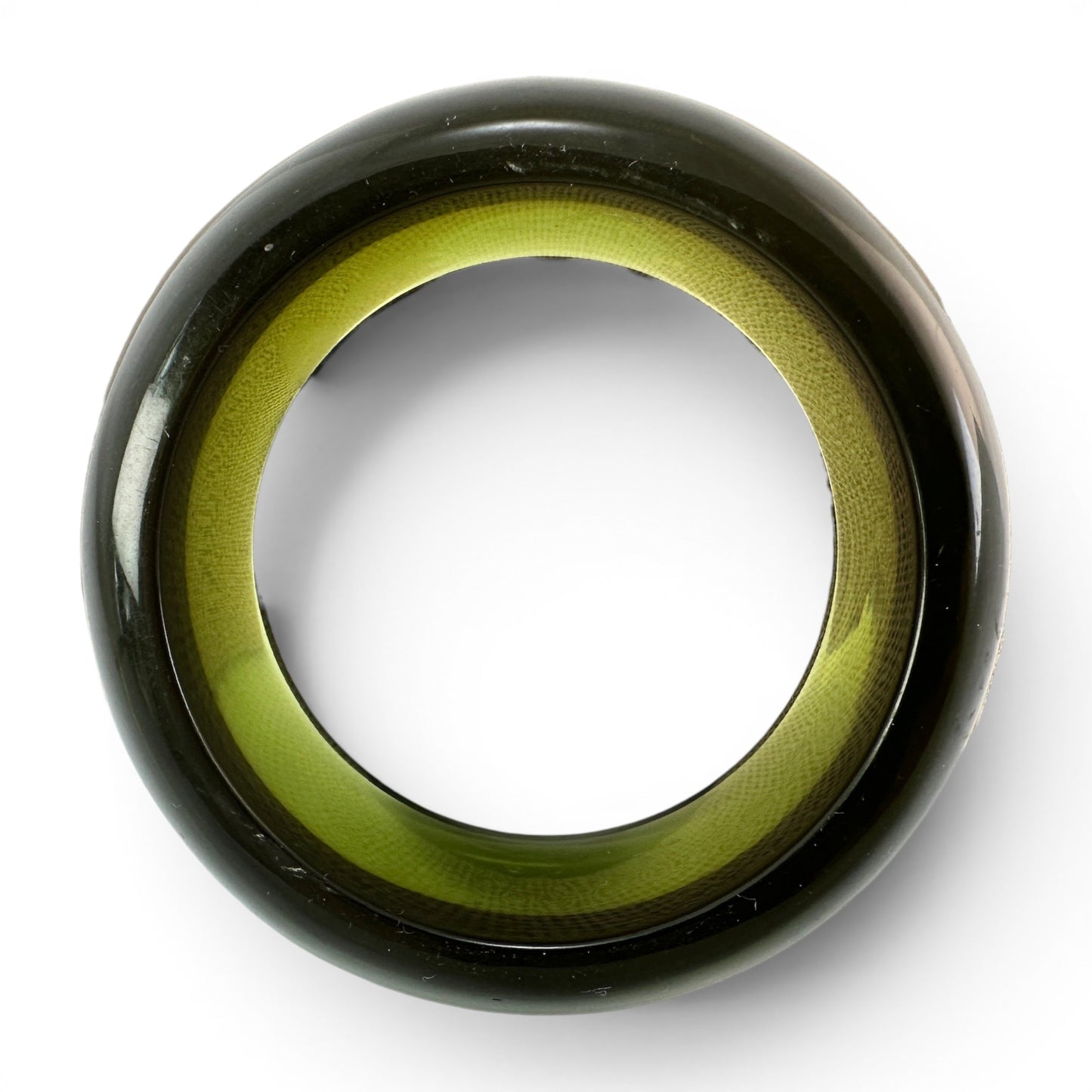 Side profile of chunky translucent Lucite bangle showing deep smoky green-black exterior surface and yellow-green interior...