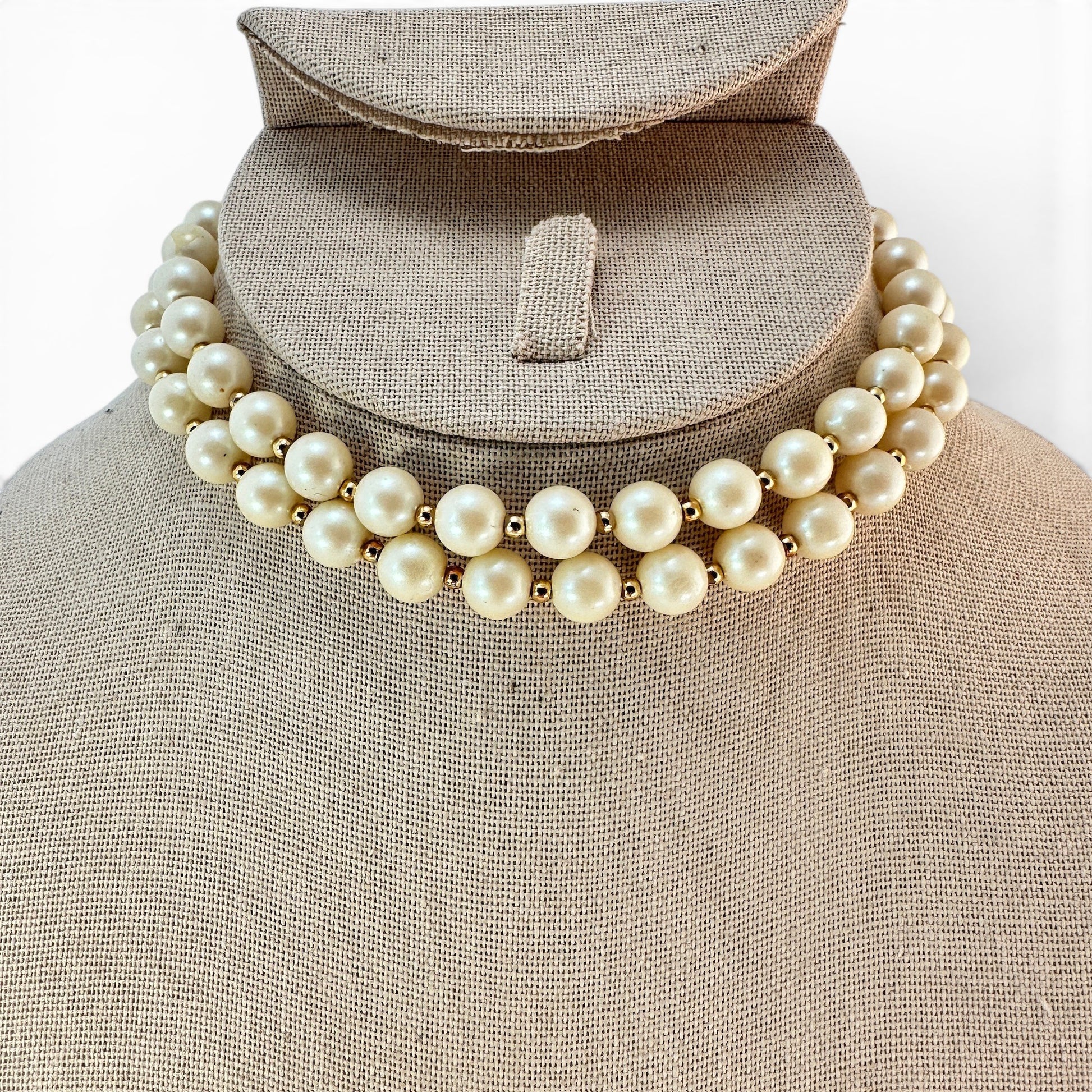 Close-up of large round ivory pearl beads with small gold-tone rondelle spacers between each bead on continuous strand