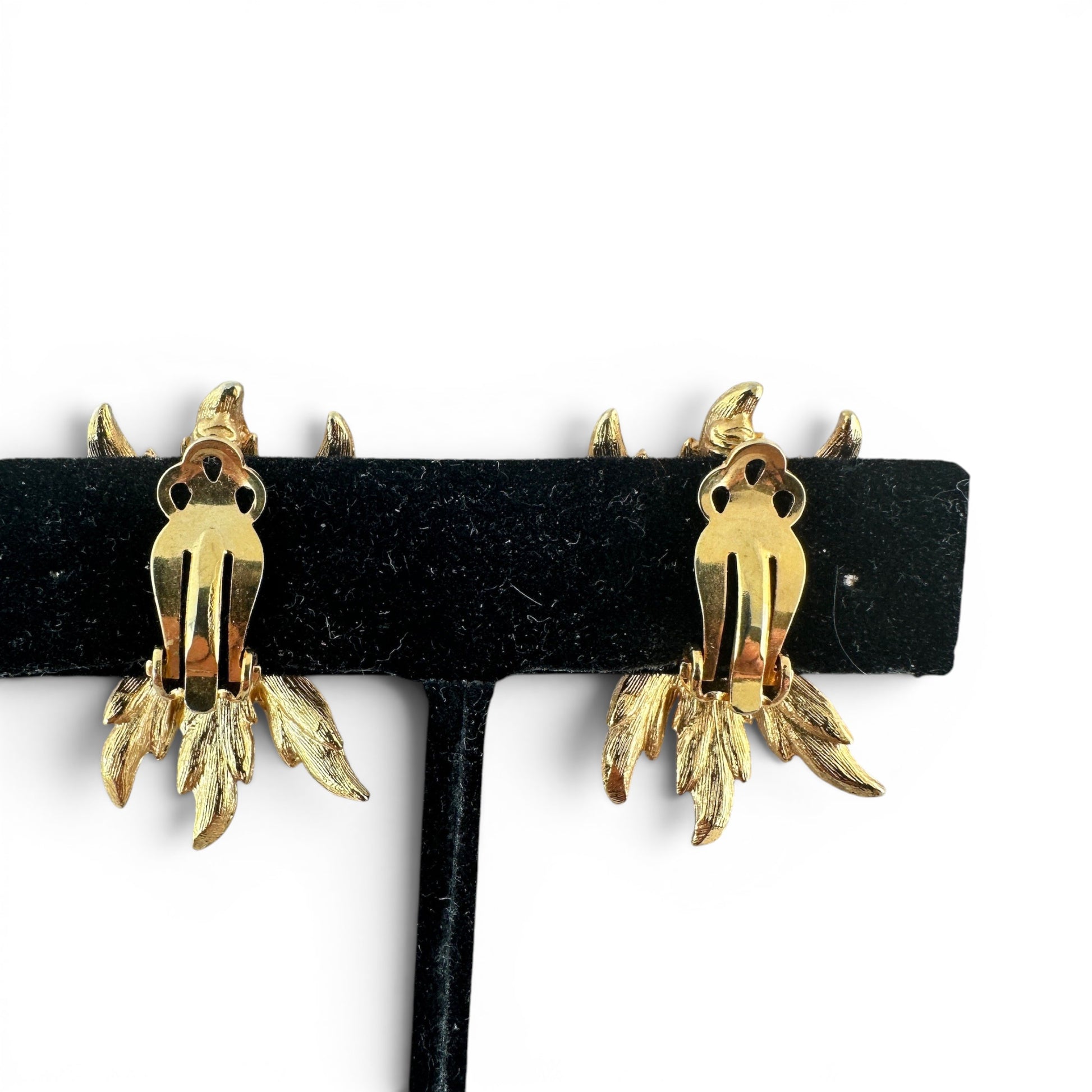 Front-facing close-up of two-tone flower form earring, outer and inner petal rings with curled petal tips and starburst si...