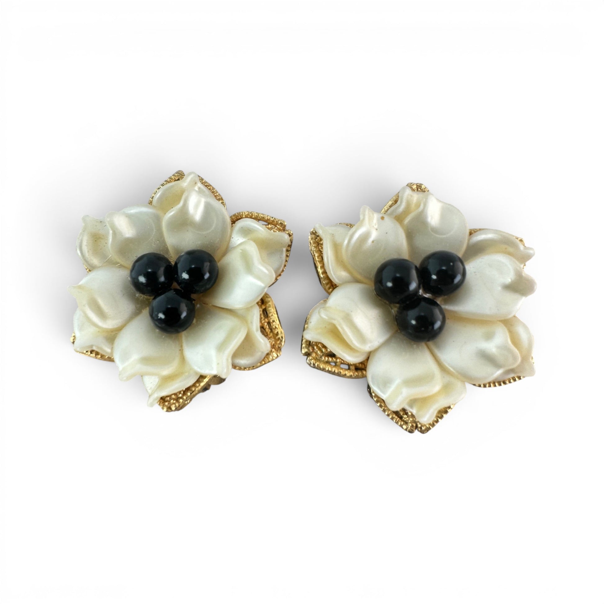 Clip-on floral earrings with layered ivory pearlescent petals and three black bead centers in gold-tone filigree frames, f...