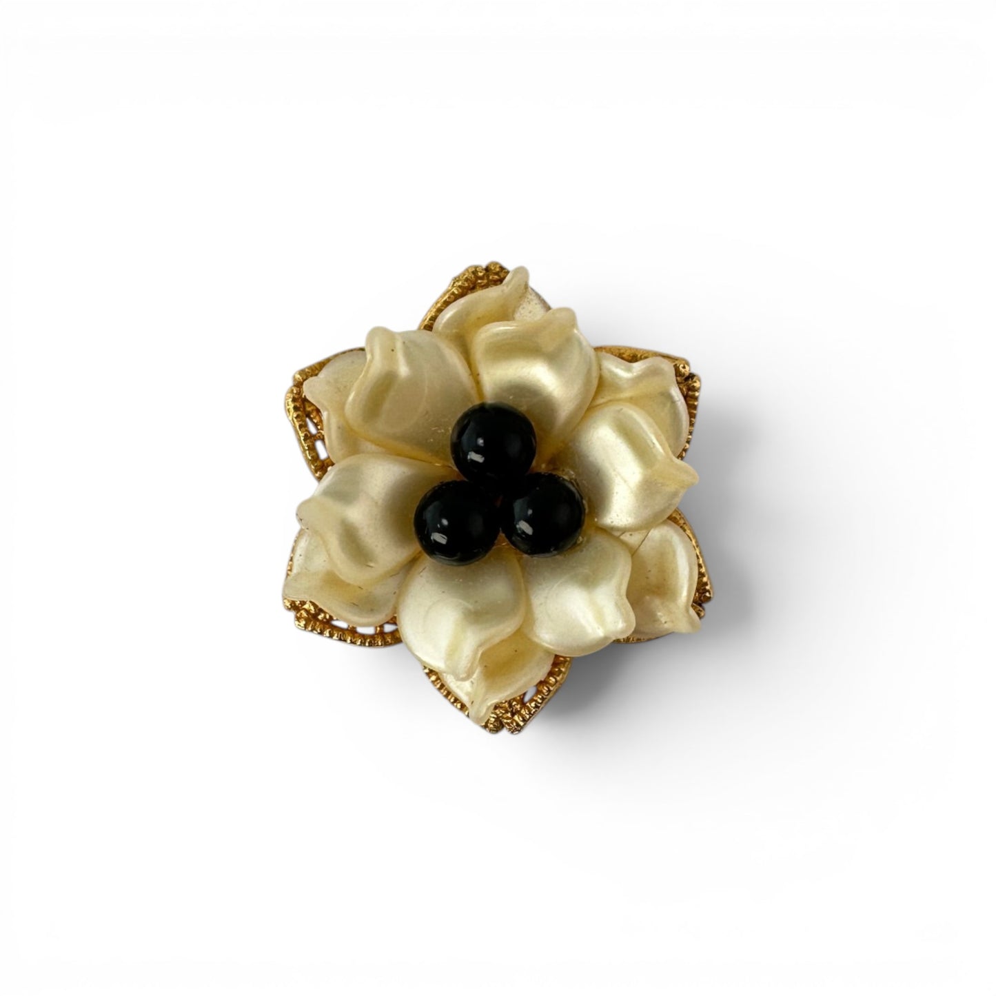 Close-up of open lattice gold-tone filigree flower base with beaded petal edges and pearlescent layered petals