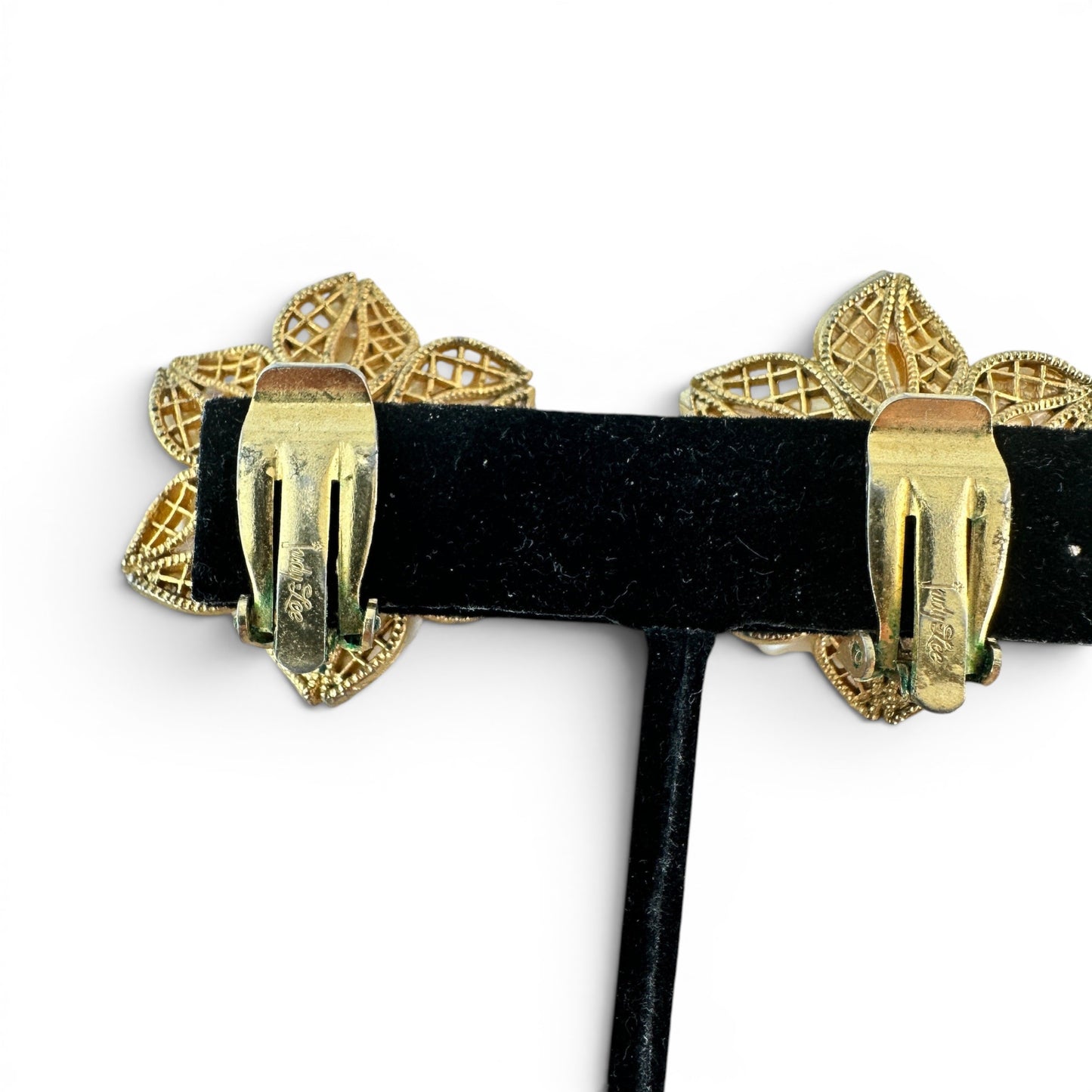 Pair of dimensional flower clip-on earrings, ivory cream petals with jet black cabochon cluster centers, angled view