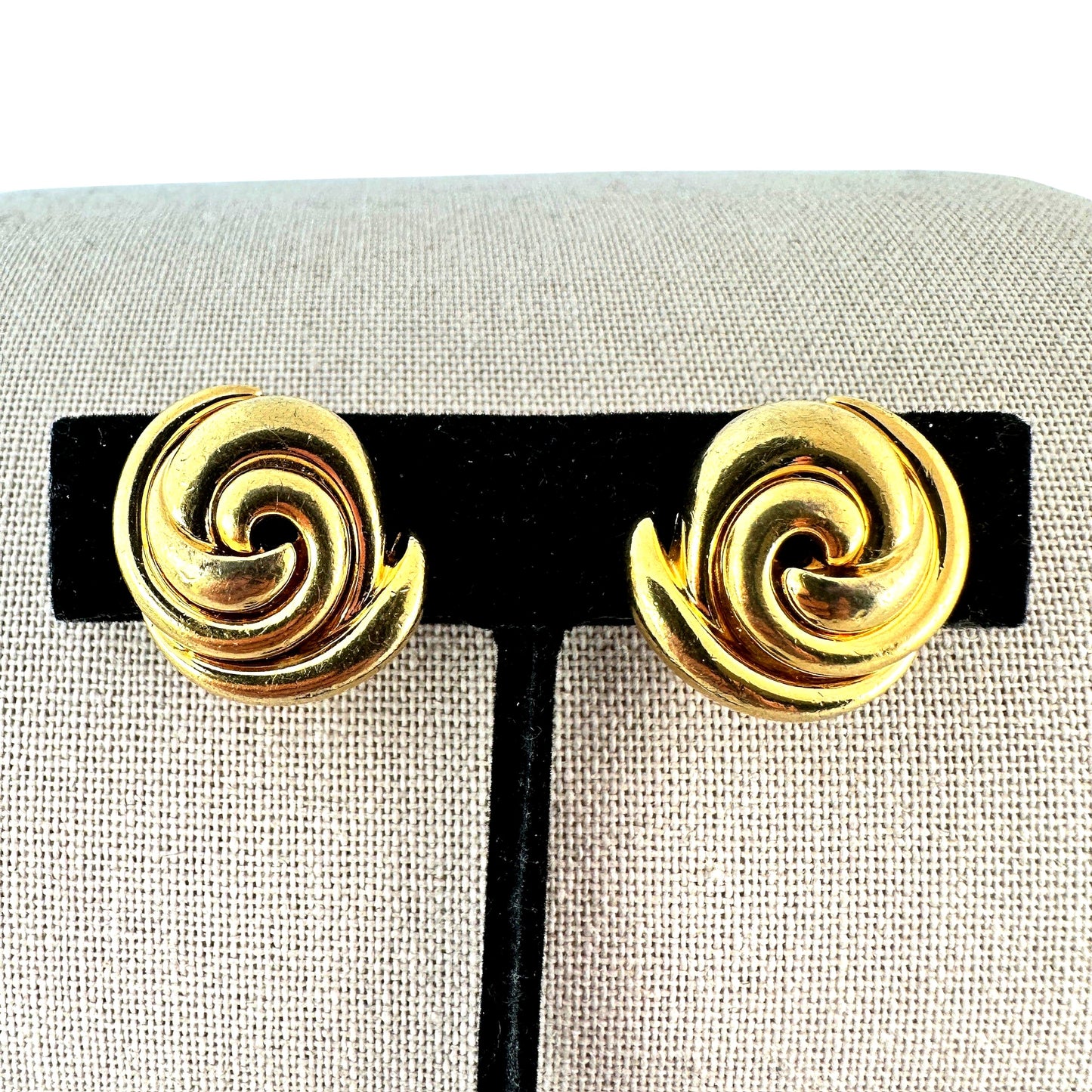 Pair of gold-tone Soleil clip-on earrings with three-dimensional nautilus spiral swirl design, high-polish finish, approx....