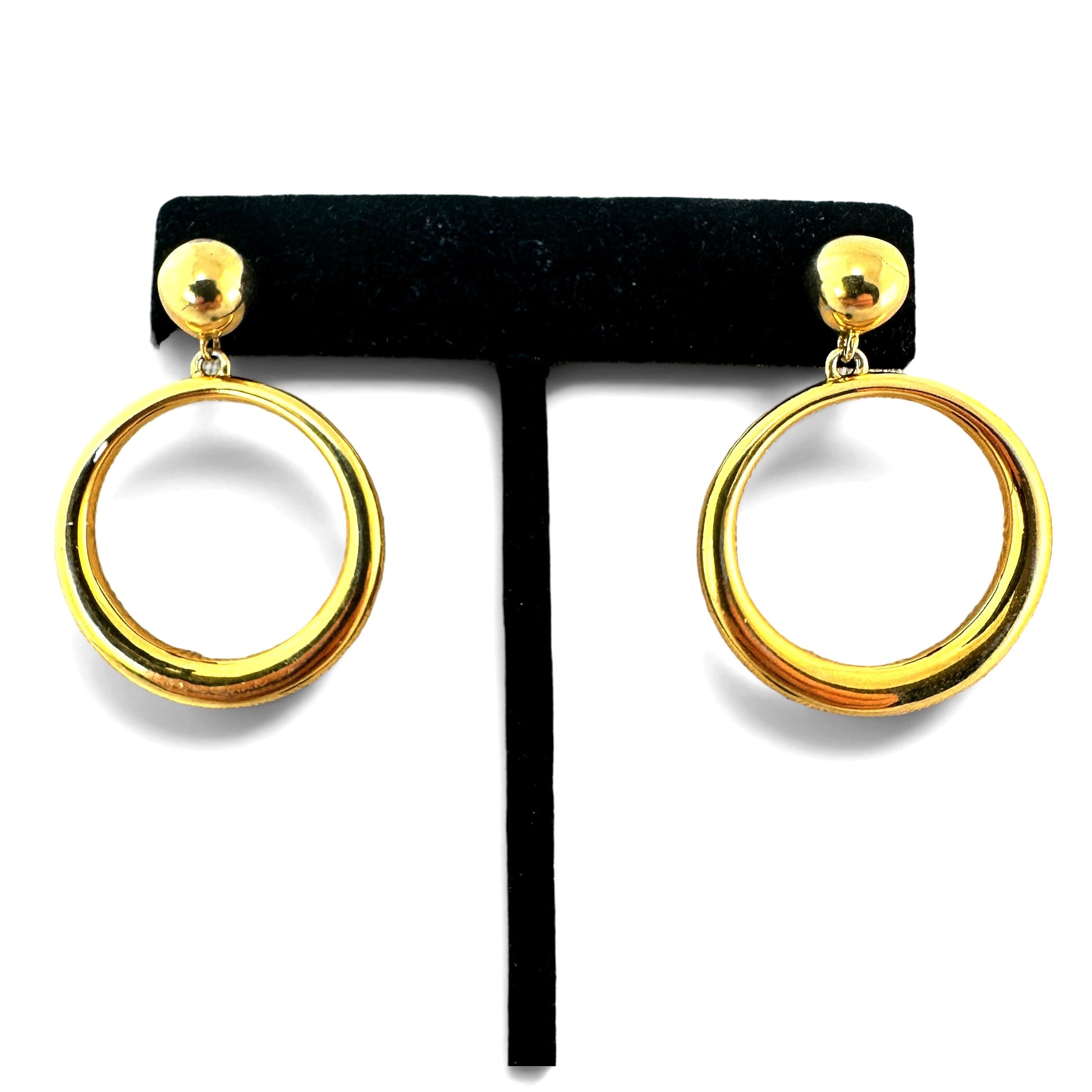 Gold-tone drop earrings with round ball stud top and large open circular tubular hoop pendant, displayed on black velvet T...