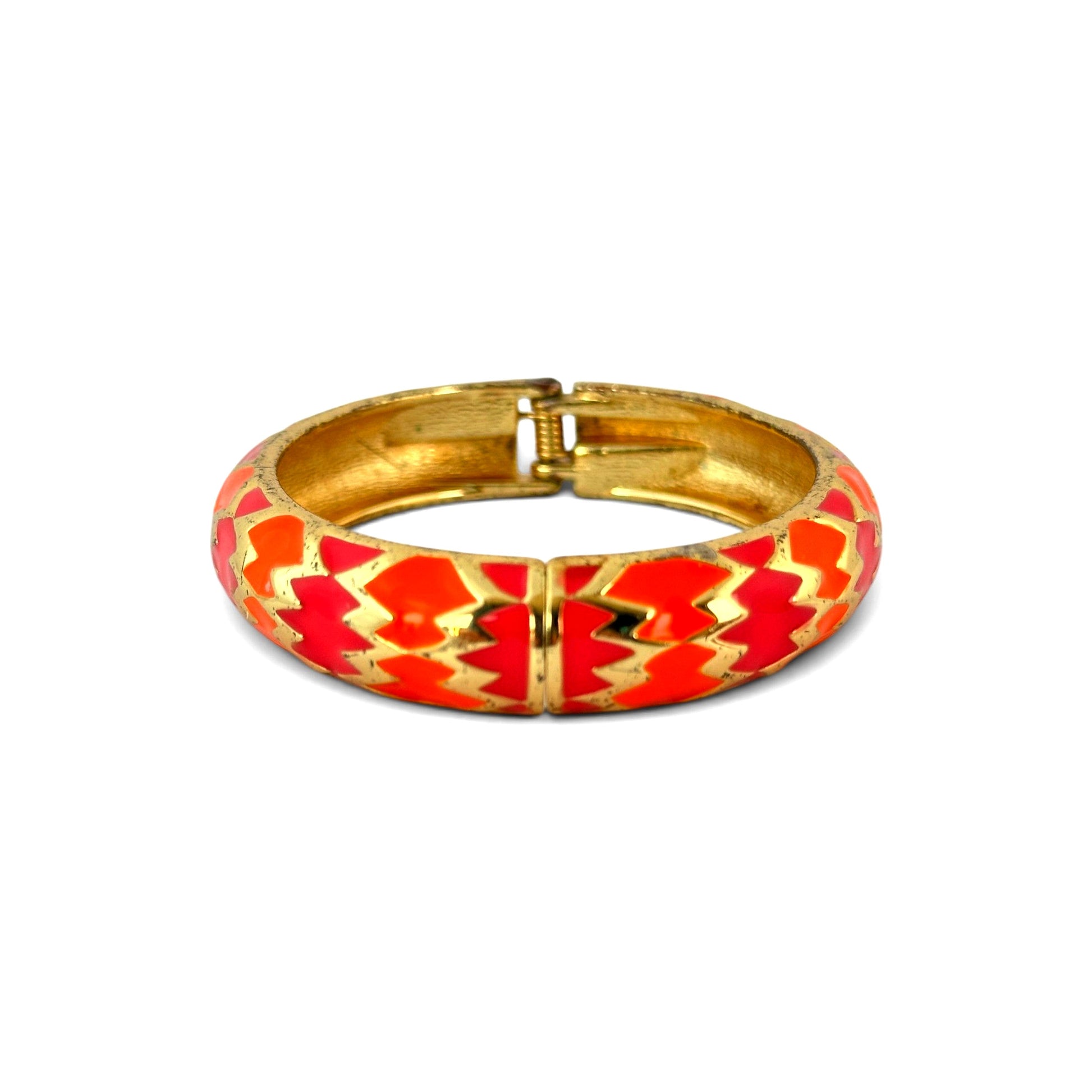 Close-up of orange and fuchsia zigzag enamel cells with raised gold-tone metal dividers on domed bangle surface