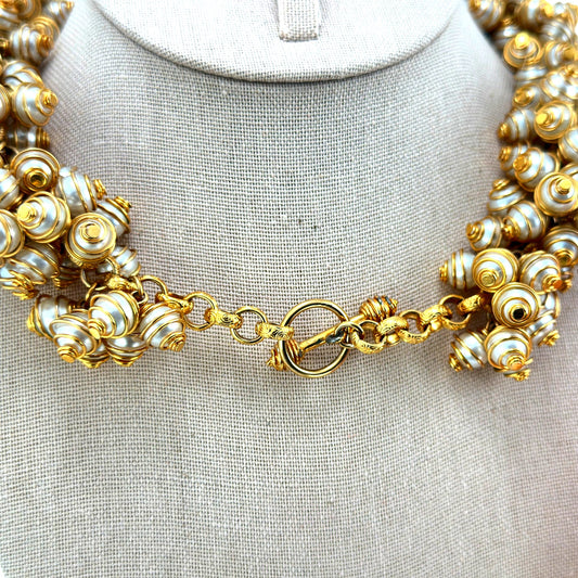 Close-up of spiral gold-tone wire-caged faux pearl beads and ornate ring-and-bar toggle clasp on bib necklace, back view