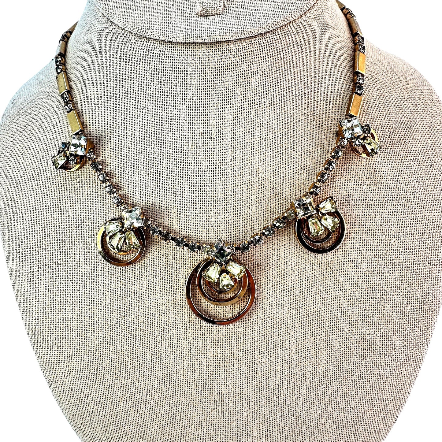 Gold-tone necklace with five concentric open-ring pendant stations each topped by mixed-cut clear and pale yellow-green rh...