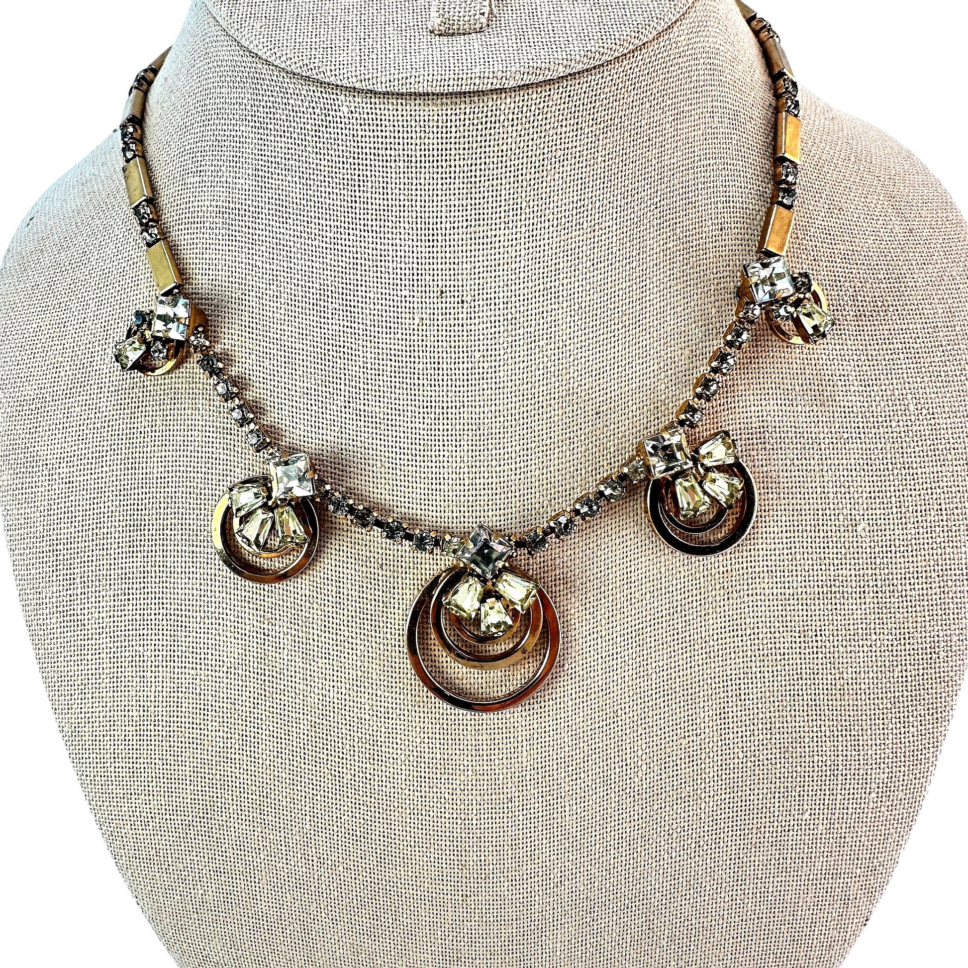 Gold-tone necklace with five concentric open-ring pendant stations each topped by mixed-cut clear and pale yellow-green rh...