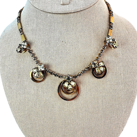 Gold-tone necklace with five concentric open-ring pendant stations each topped by mixed-cut clear and pale yellow-green rh...
