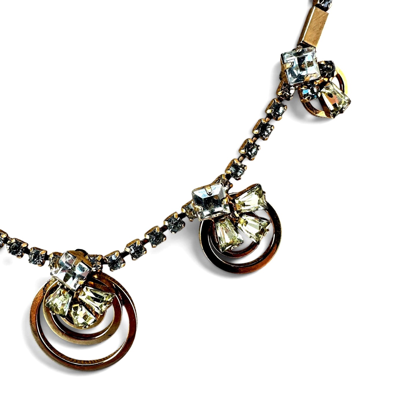Close-up of concentric open-ring pendant station showing oxidation and patina on gold plating with mixed-cut rhinestone cl...