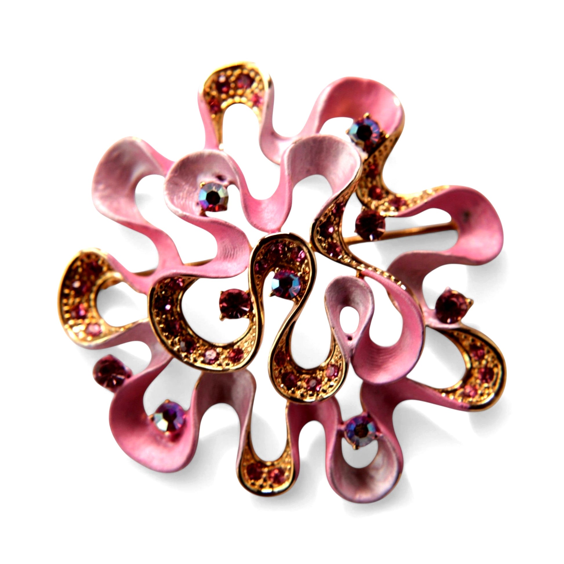 Circular openwork brooch in gold-tone metal with pink enamel swirl forms, prong-set pink and amethyst rhinestones, and aur...