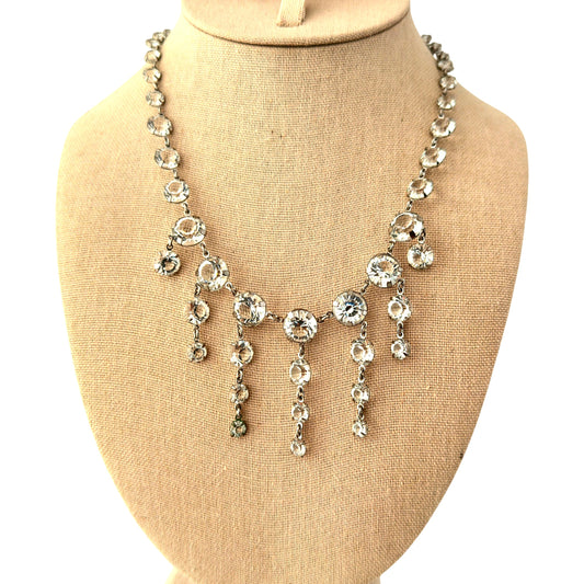 Silver-tone rhinestone bib necklace with five cascading pendant drops of graduated clear crystal stones on white background