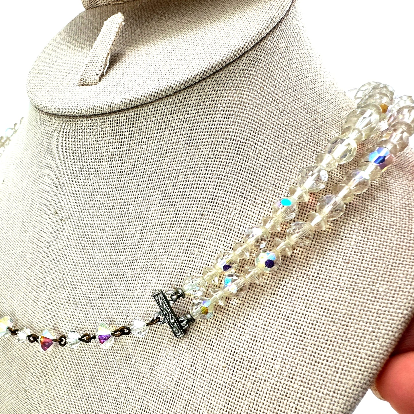 Close-up of graduating faceted aurora borealis crystal beads, largest beads at center front of lower strand