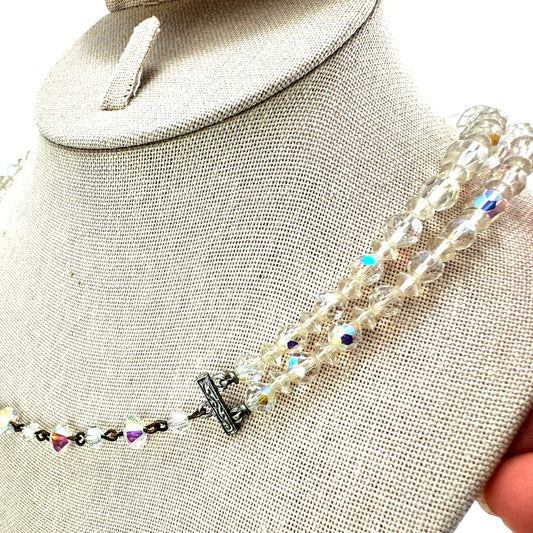 Close-up of graduating faceted aurora borealis crystal beads, largest beads at center front of lower strand