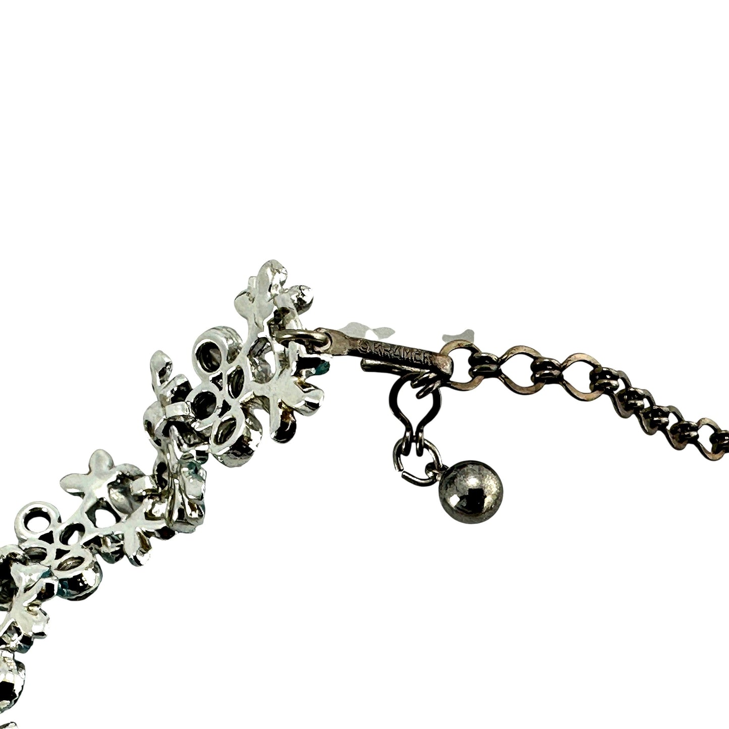 Detail of hook-and-eye clasp with extender chain and ball drop stamped KRAMER on silver-tone bar