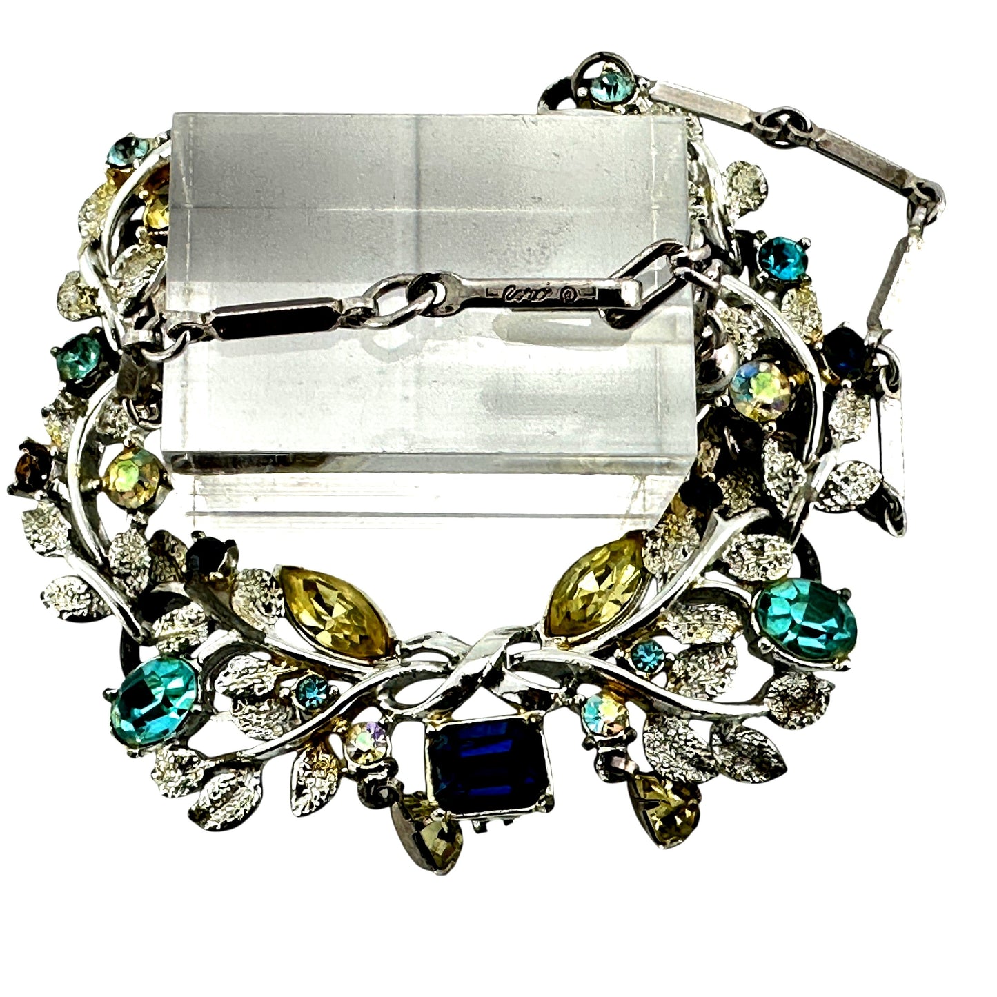 Detail of pear-shaped yellow-green drop stones hanging from jump rings at base of Coro foliate necklace centerpiece